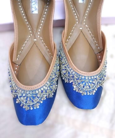 Elegant blue festive juttis featuring intricate silver hand embroidery and tan leather lining