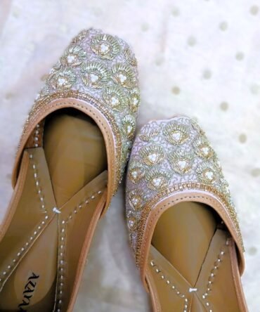 Close-up of Noorani Juttis showcasing gold zardozi and pearl embroidery on lilac silk base