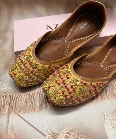Close-up of yellow Mehak Punjabi juttis with festive embellishments